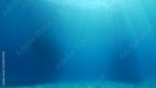 silhouette of boats in blue water with sun rays and beams underwater
