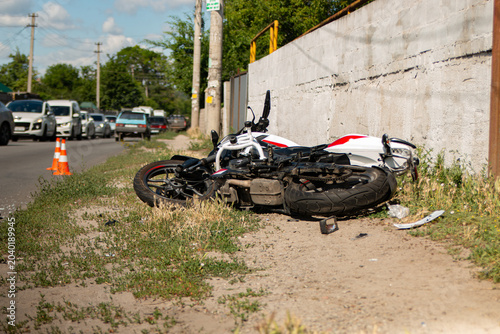 Fotografie Motorcycle crash scene on a city street with damaged bike on the roadside