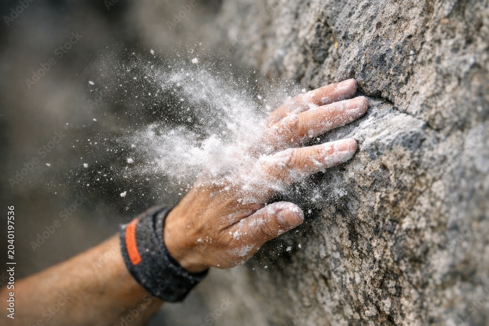 Fototapeta premium A person's hand stretching towards an object on a rocky surface