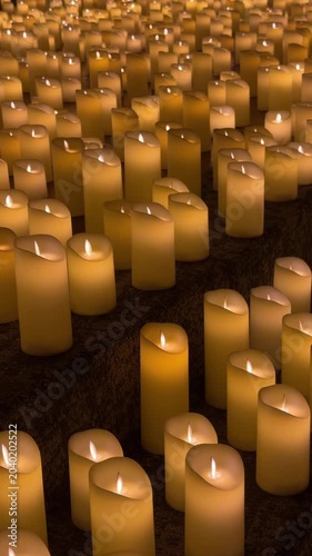 Slow pan of rows of lit candles burning on stone steps inside dim interior with warm golden glow and shallow depth of field