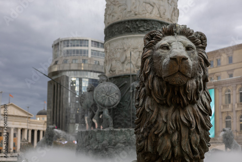 bronze lion statue guard at warrior on a horse fountain in skopje macedonia square dramatic moody sky stock photo perfect for travel and balkan history