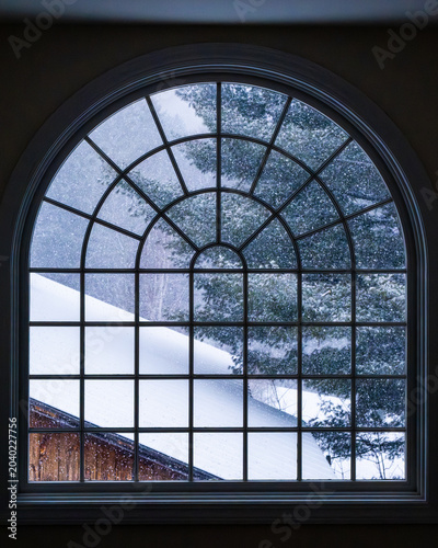 Snowy scene from inside looking out through an arched window.