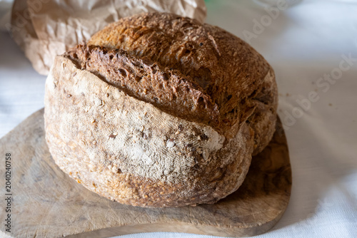 Foto Rustic Neapolitan farmer's sourdough loaf with whole grains on wooden board, tra