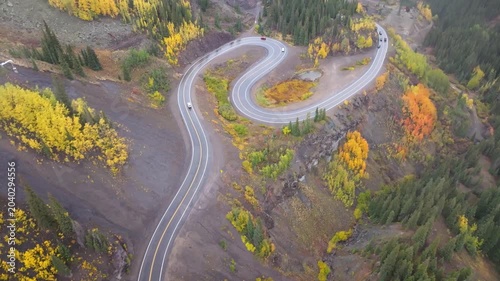Aerial view of cars on winding road in Colorado fall landscapes along Million Dollar Highway with views of fall foliage trees in San Juan Mountains during autumn season - 4K Drone