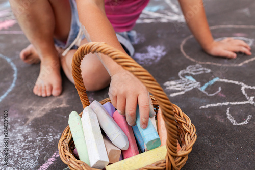 Little girl doing chalk drawing activity on driveway at home making artwork