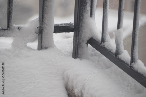 Billede på lærred Snow covers railing and ground in urban area during winter