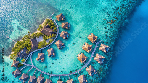 Aerial view of overwater villas and tropical island resort in turquoise lagoon