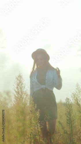 Sunlit rural scene, Softly illuminated meadow scene featuring woman walking peacefully through tall grasses