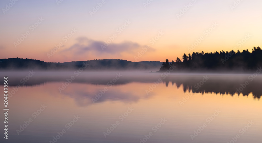 Obraz premium Serene Sunrise Over Calm Lake with Misty Forest Reflection