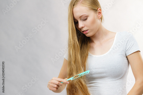 Foto Woman combing long healthy blonde hair