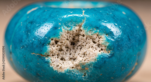 Ancient glazed ceramic bead with damage, close-up