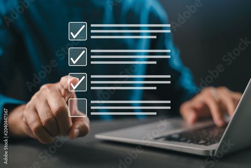 Finger selecting virtual checklist interface, task management planning, business professional executes productivity decision through digital workflow using laptop computer at desk