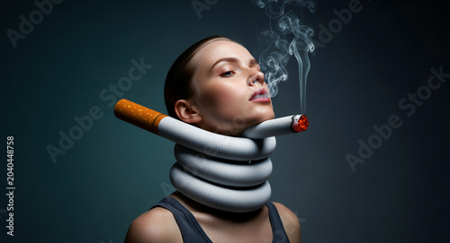 Young woman with a giant burning cigarette wrapped around her neck. Surreal conceptual portrait illustrating the suffocating nature of nicotine addiction. Anti-smoking health campaign concept.