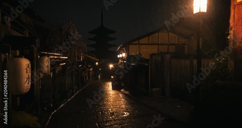 Beautiful rain fall on ancient Japanese village at night with silhouette of tower - steady cam shot