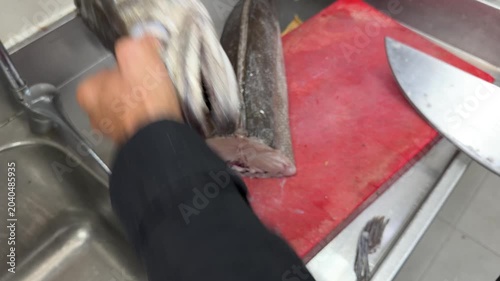 Professional chef cleaning fresh fish in a restaurant kitchen