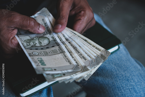 Indian Man hands counting Indian Rupees banknote. Money depreciation against dollar concept. Cropped image, copy space, selective focus.