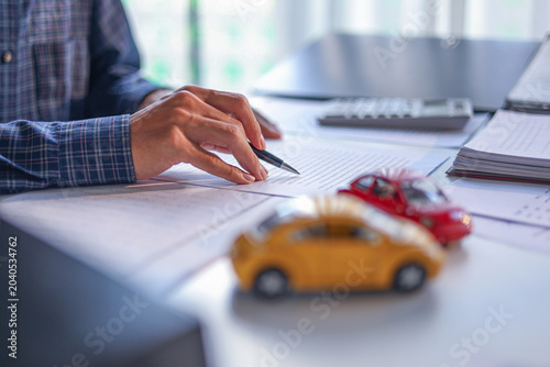 Bild auf Leinwand A man signing a contract for a car loan, lease, vehicle registration or insurance policy