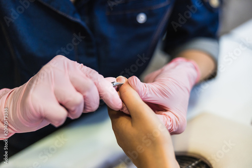 Nail technician performing manicure in beauty salon