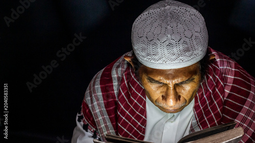 Foto a muslim man is reading the quran at night