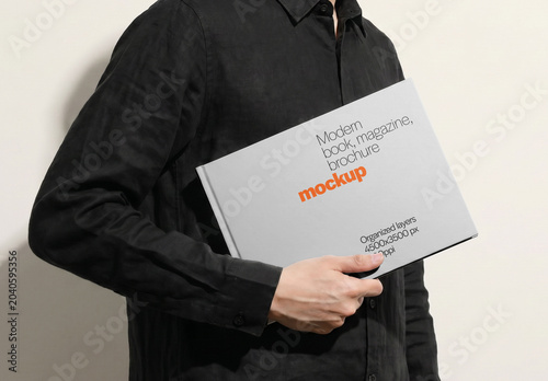Hardcover Book Mockup Held Horizontally Under Arm By Man Side View On Light Background