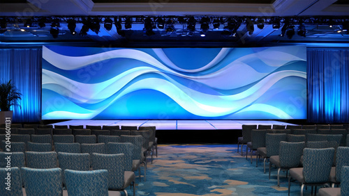 Modern Conference Hall Stage with Large Blue LED Screen and Rows of Empty Seating for Corporate Event