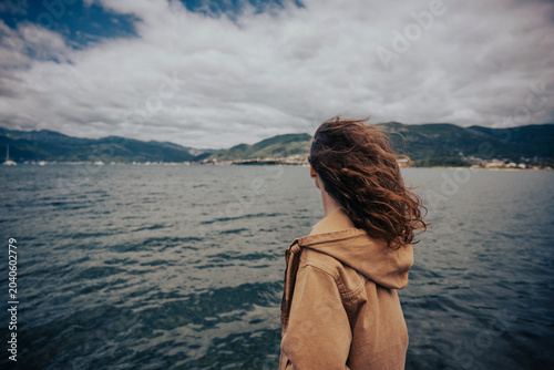 Obraz na plátně Moody and atmospheric portrait of a woman by the sea bay on a breezy day