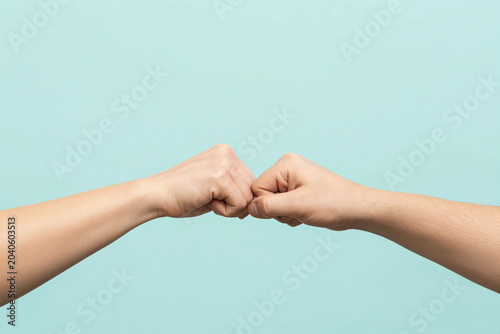 Close up shot of couple two male friends men together hold hands folded fist bump gesture isolated on pastel plain light blue cyan color background studio portrait. Friendship business greet concept.