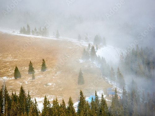 Tableau sur toile Small cabin nestled in clearing on mountainside, surrounded by dense pine forests