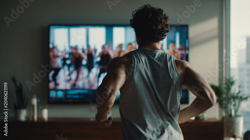 man doing exercises next to the TV fitness workout program