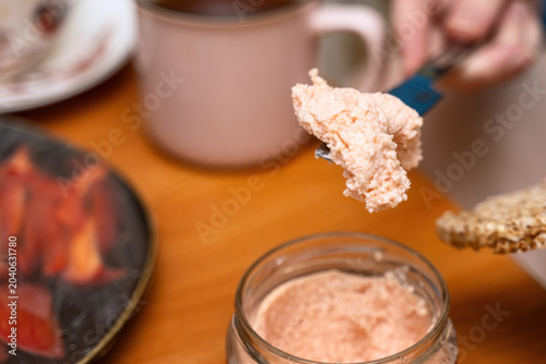 Spreading river fish and seafood roe paste on a crispbread with a metal knife during breakfast. Savory morning toast idea
