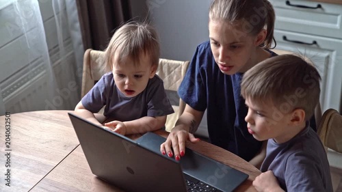 Child explores keyboard. Young child investigates computer keys. Toddler and mother share playful keyboard exploration moment. Mother and young child delight in discovering laptop keys together