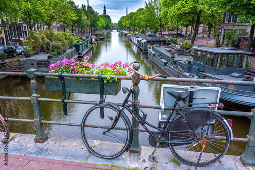 Canvas Print Altes Fahrrad lehnt an Geländer über einer Gracht in Amsterdam