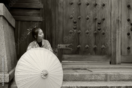 Young Woman in Blue Kimono Behind Paper Umbrella at Japanese Shrine Gate, in sepia black and white