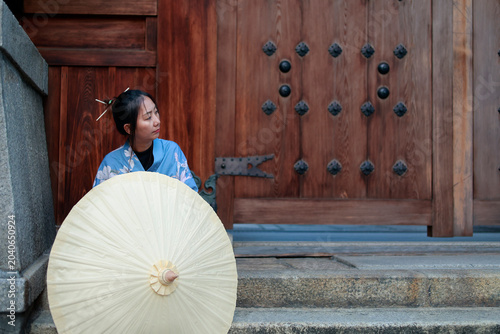 Young Woman in Blue Kimono Behind Paper Umbrella at Japanese Shrine Gate