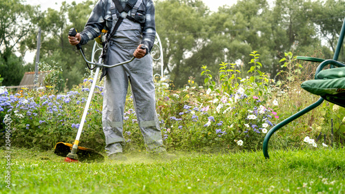 Man trims grass with a powerful weed wacker