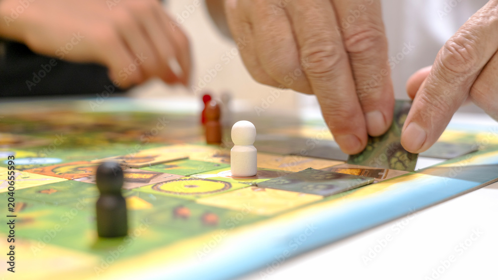 Obraz premium Hands move pieces on a colorful board game