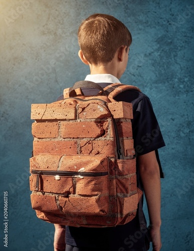 Brick backpack on a young student boy seen from behind for mental health awareness, academic pressure concepts and school stress campaigns with copy space