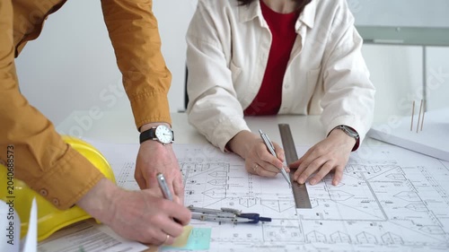 Engineering team collaborating on architectural blueprints, reviewing construction plans, and discussing building design concepts with tools and safety hard hat on table