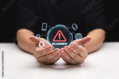 Security alert showing scammer warning icon held between hands over dark background for cyber safety.
