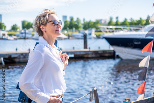 Canvas-taulu Elegant senior woman in sunglasses looking into distance by marina with luxury y