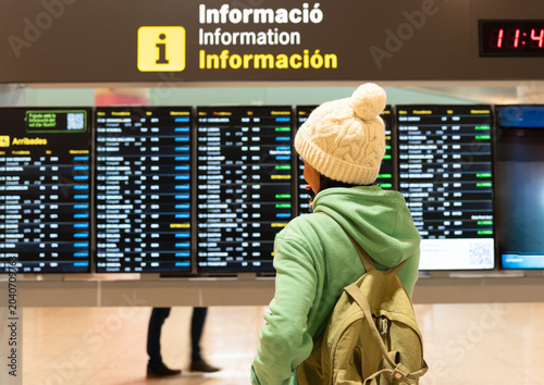 Bild auf Leinwand Traveler finding flight information on airport arrivals departure board, checkin