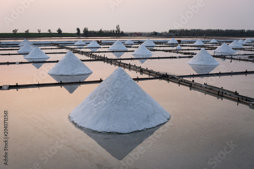 Φωτογραφία Traditional salt evaporation ponds with numerous white conical piles of harveste