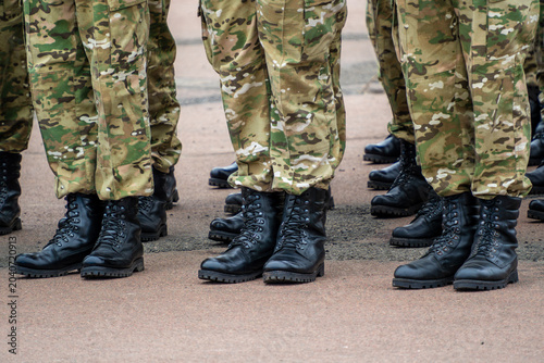 Φωτογραφία legs and feet of several soldiers standing in formation on an asphalt surface