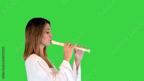Beautiful brown-haired girl walks playing the flute on a Green Screen, Chroma Key.