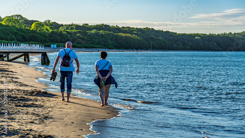 Senior couple walking along sandy beach on a sunny day by the Baltic Sea