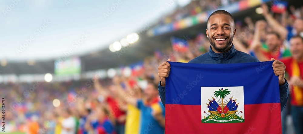 Fototapeta premium Haitian football fan celebrating with national flag in stadium