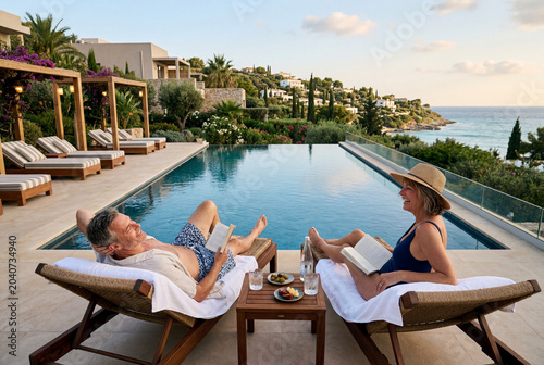 mature married couple on sunbeds next to a swimming pool