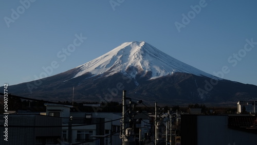Fotografie Snow-capped Mount Fuji volcano rising above harbour under clear blue sky, Japan