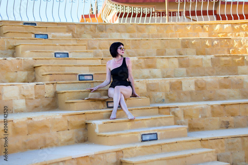 Fényképezés woman in a bikini on the steps of old amphitheater.