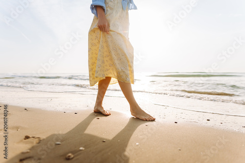 Foto A woman walks barefoot on wet sand by the ocean